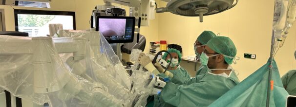 In einem Operationssaal operieren zwei Ärzte mit Hilfe eines Roboters und eine Operationstechnische Assistentin unterstützt.